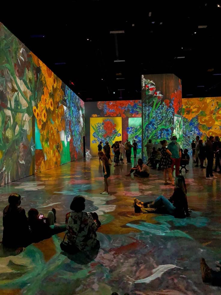 Immersive art exhibition with colorful floral projections and people observing the vibrant displays.
