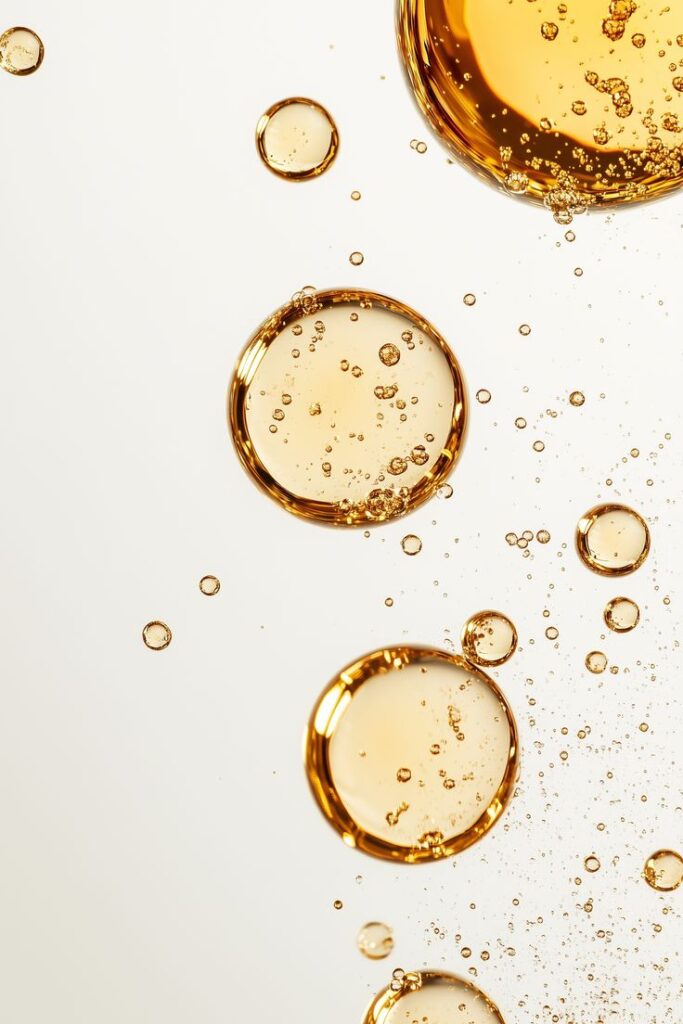 Golden oil bubbles suspended in clear liquid, showcasing texture and detail in a vibrant, close-up view.