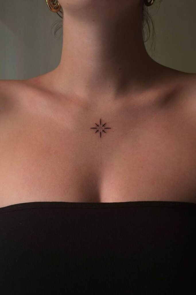 Minimal starburst tattoo on woman's upper chest, wearing a black strapless top.