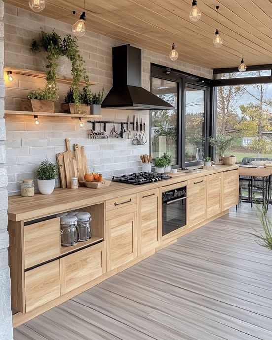 Modern kitchen with wooden cabinets, plants, and a large window for natural light. Cozy and stylish design.