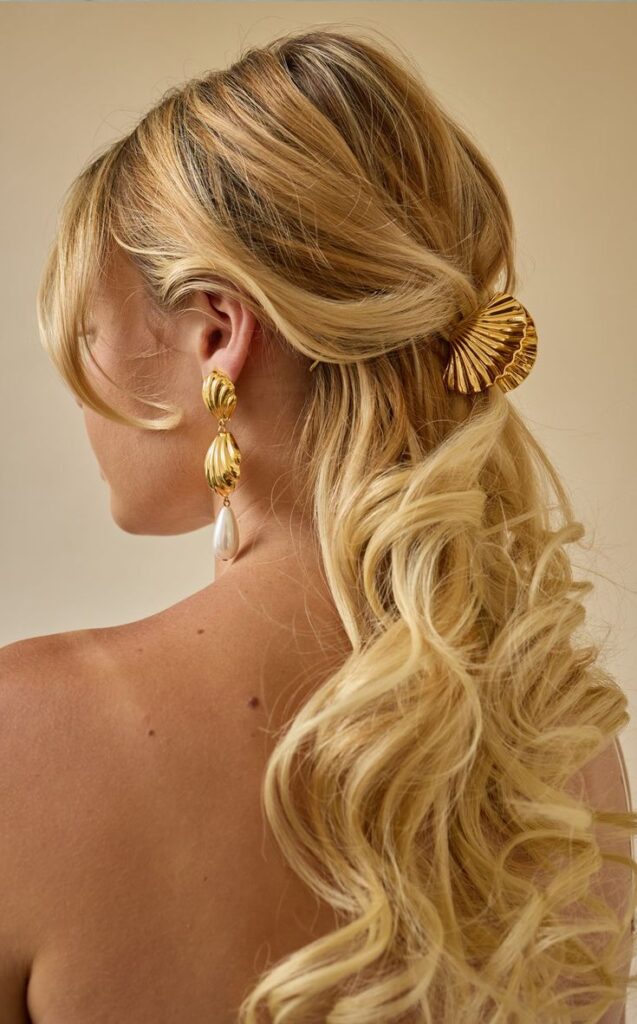 Blonde hair with gold shell clip and pearl earrings, elegant hairstyle inspiration for fashion-forward women.