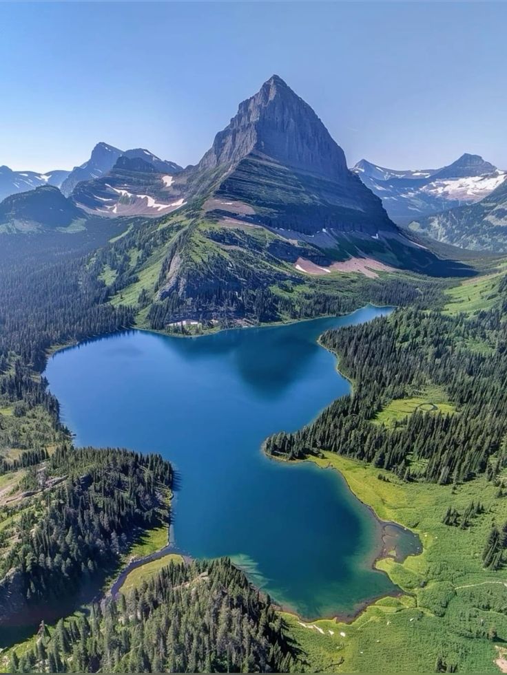 Majestic mountain and serene lake surrounded by lush greenery and forests under a clear blue sky.