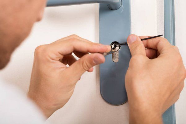 Person picking a door lock with tools, close-up of hands and lock. Security or locksmith concept.
