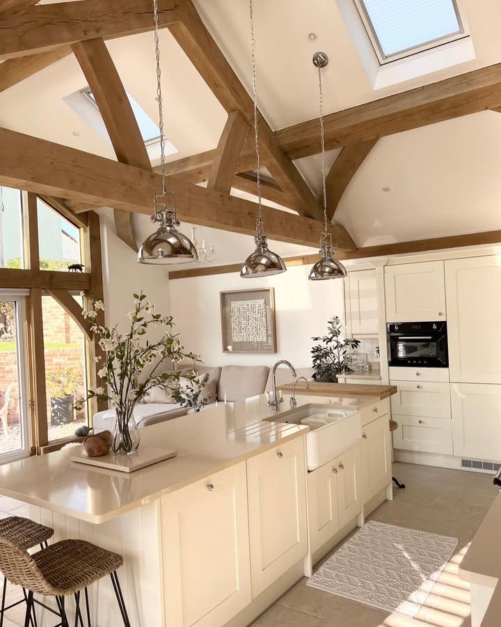 Bright modern kitchen with vaulted ceilings, skylights, wooden beams, island, and pendant lights. Cozy and elegant design.