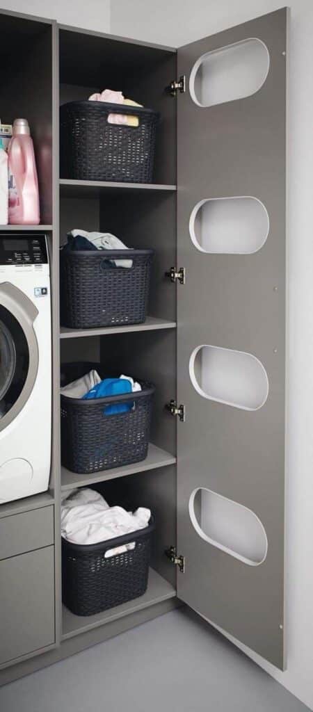 Modern laundry room with gray shelves, black baskets, and a washing machine. Organize laundry essentials efficiently.