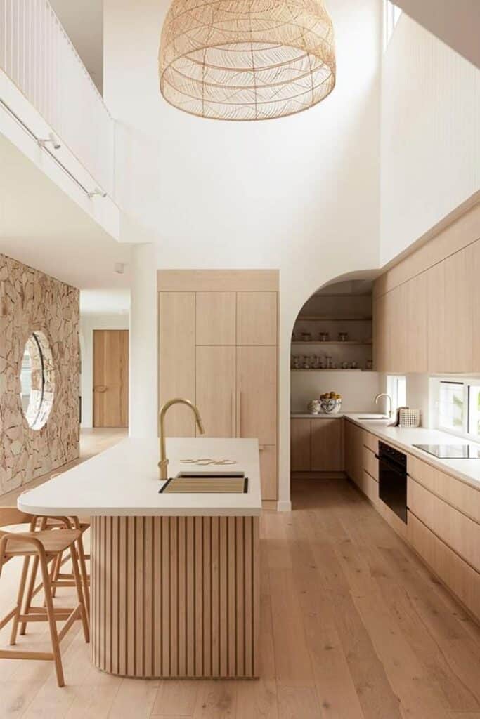 Modern kitchen with light wood cabinets, island, and open shelving, featuring a woven pendant light.