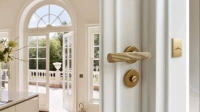 Elegant French doors with a gold handle open to a sunny patio, blending indoor and outdoor spaces seamlessly.