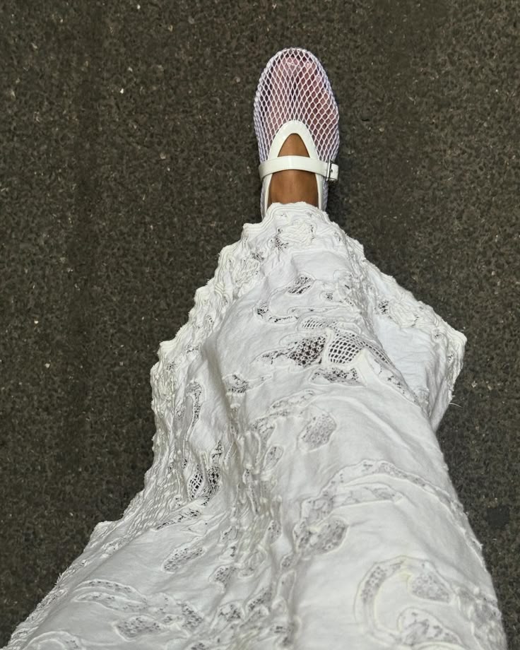 White mesh shoe and detailed lace dress on asphalt road, top view. Fashionable outdoor walking style.