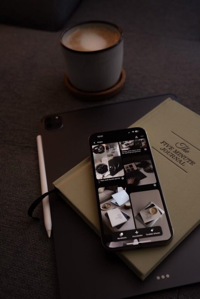Modern workspace with a smartphone, journal, tablet, and coffee cup on a cozy surface.