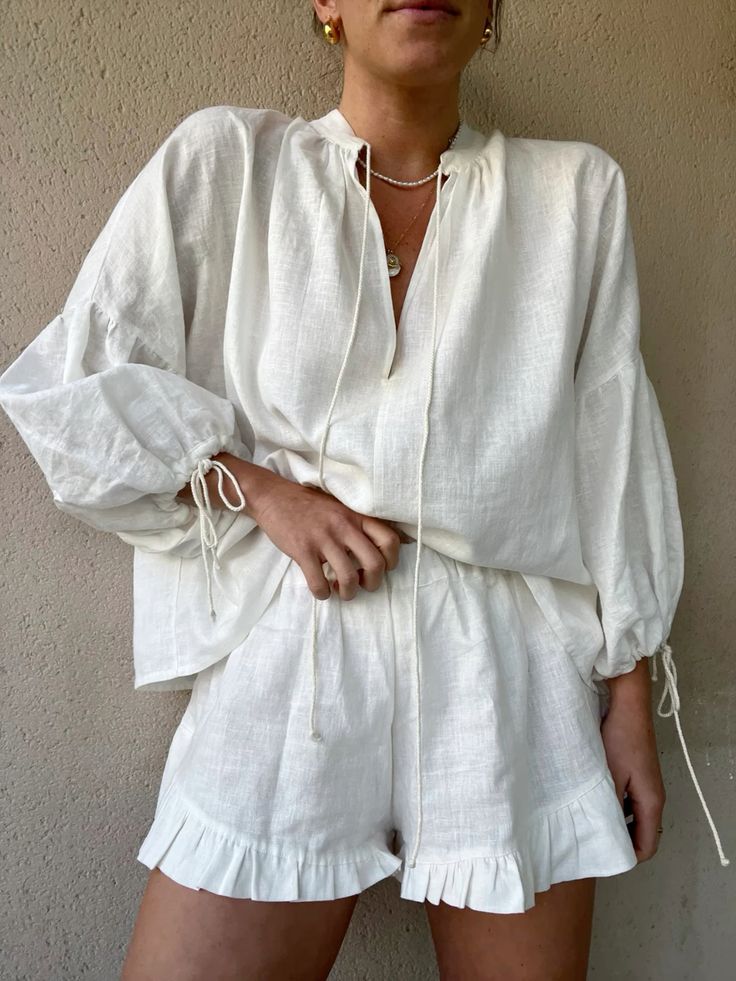 Woman wearing a stylish white linen matching set with a loose blouse and ruffled shorts.