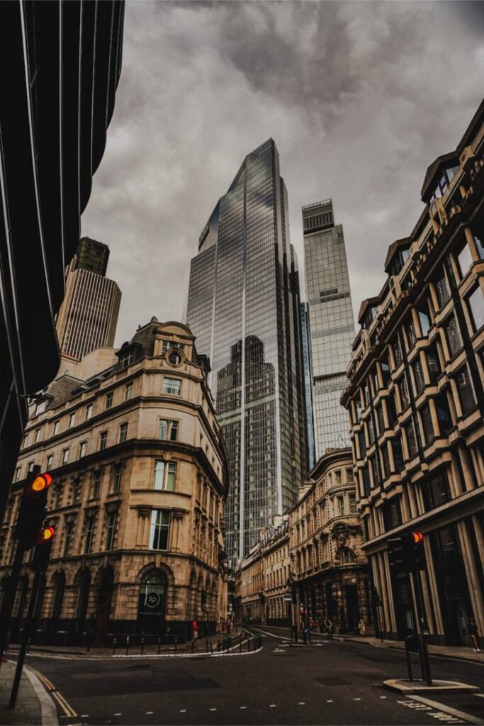 Tall modern skyscraper among historic buildings under a cloudy sky in an urban landscape.