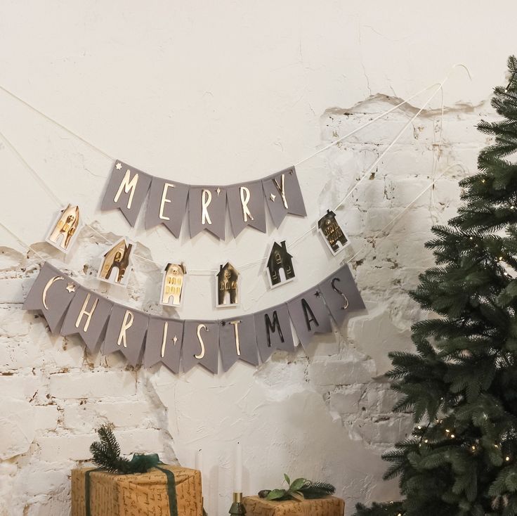 Merry Christmas banner with festive decorations and a pine tree against a white brick wall.
