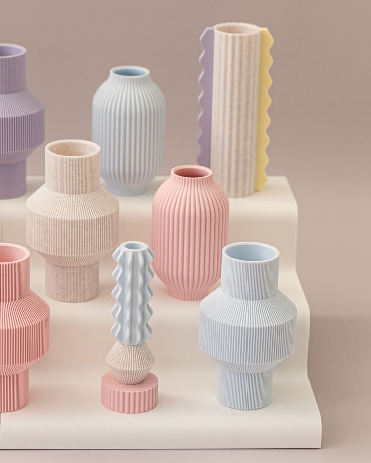 Elegant pastel vases with ribbed textures on display shelf, showcasing modern ceramic home decor.