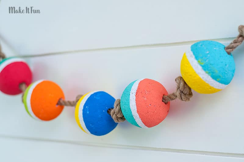 Colorful DIY foam ball garland on rope against white wall background.
