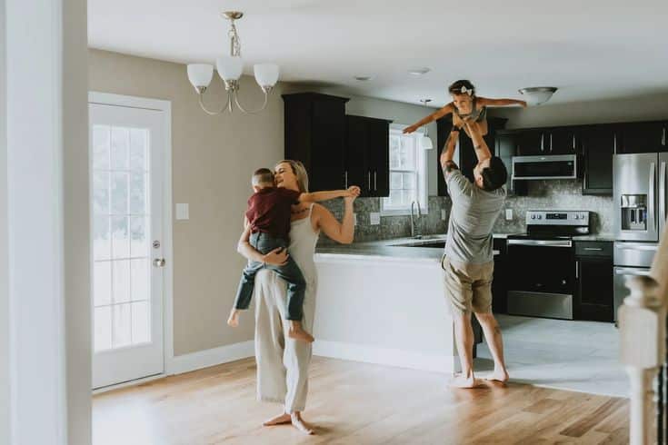 Family enjoying quality time in a spacious, modern kitchen with children being lifted and embraced.