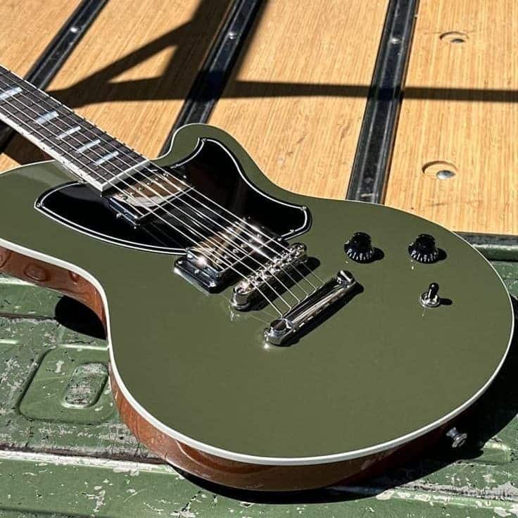 Olive Green 💚 Olive green electric guitar on a textured surface, showcasing its sleek design and metallic accents. | Sky Rye Design Olive green electric guitar on a textured surface, showcasing its sleek design and metallic accents.