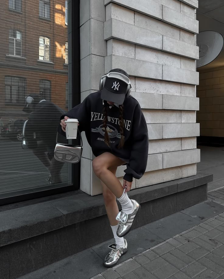 Trendy outfit with oversized sweatshirt, headphones, and coffee cup on city street. Urban fashion and casual style.
