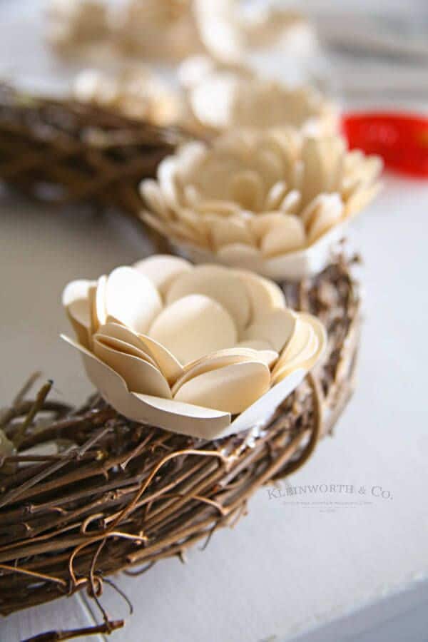 Close-up of a woven wreath with handcrafted paper flowers, perfect for home decor and floral DIY projects.