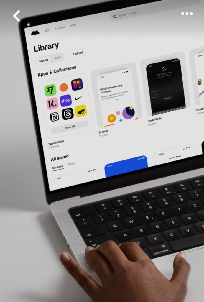 Laptop screen displaying app library, with hand on keyboard. Features app icons and categories for mobile and web.