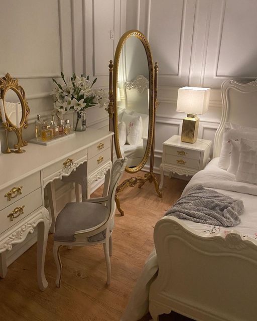 Elegant bedroom with vintage vanity, full-length mirror, and ornate decor. Cozy, luxurious ambiance.