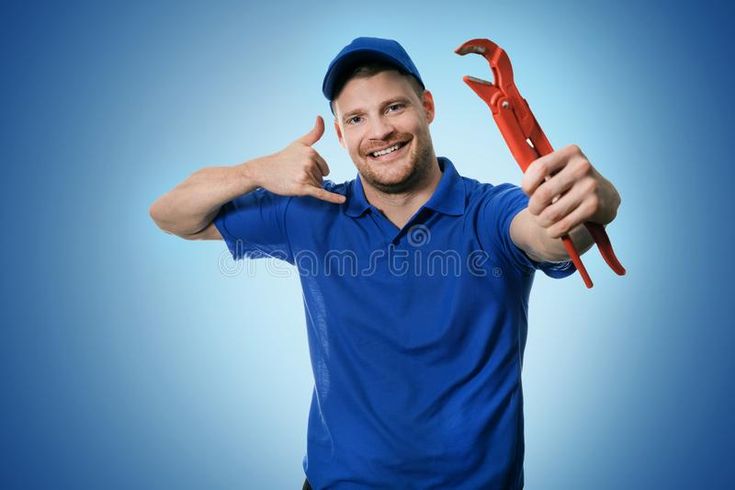 Man in blue uniform smiling and holding pliers, making a call gesture, indicating plumbing services on blue background.