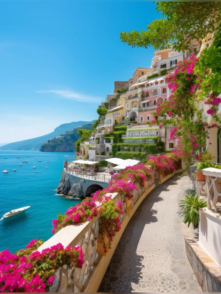 Colorful seaside buildings and vibrant flowers overlooking a bright blue ocean in Positano, Italy.