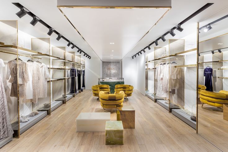Luxury clothing store interior with modern design, elegant racks, and plush yellow seating, showcasing chic apparel.