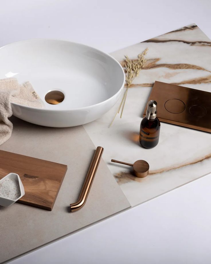 Modern bathroom accessories with a white vessel sink, copper fixtures, and marble countertop.