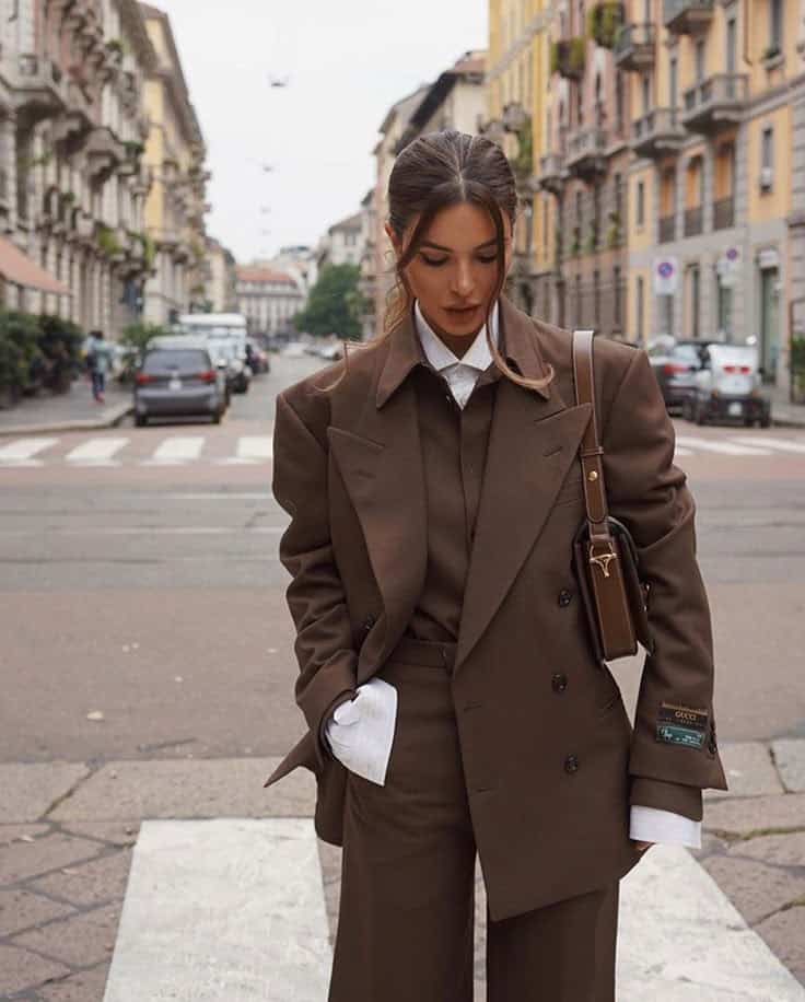 Woman in stylish brown suit walking on an urban street, showcasing fall fashion trends.