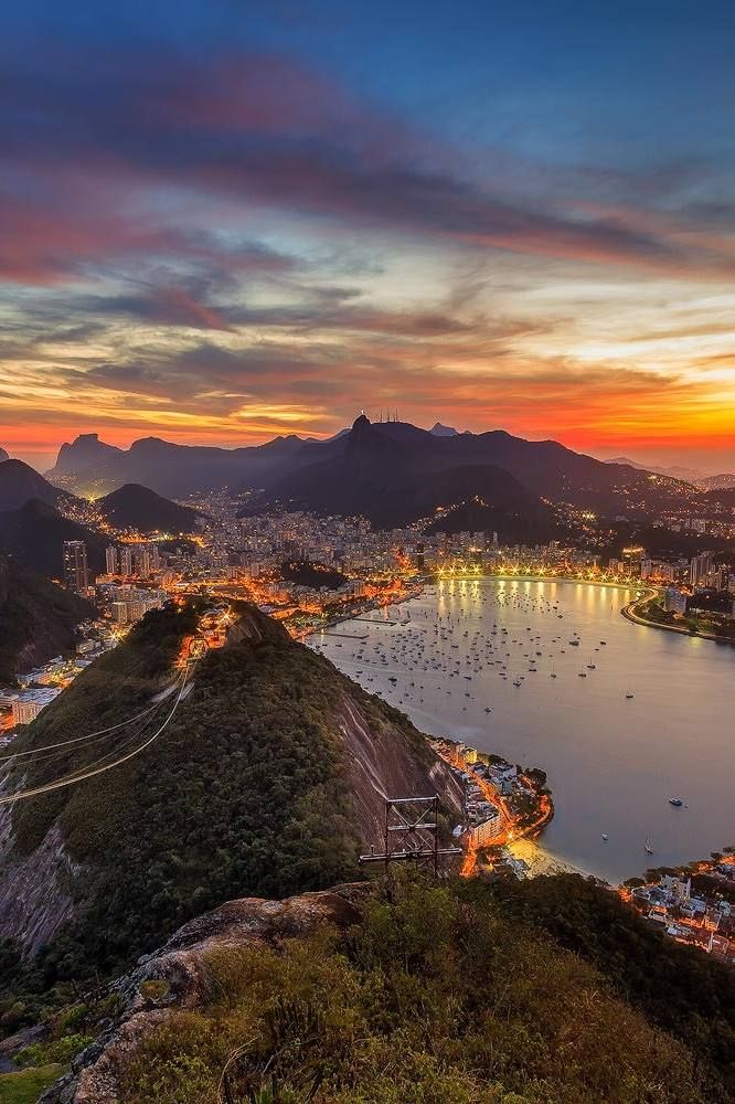 Sunset over Rio de Janeiro with Sugarloaf Mountain and city lights illuminating the bay.