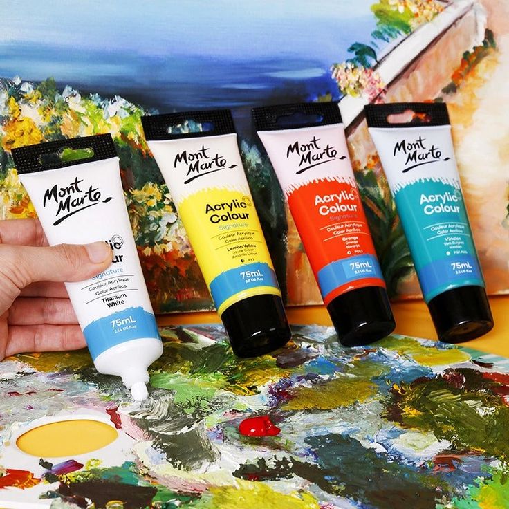 Tubes of Mont Marte acrylic paint in white, yellow, red, and blue, displayed on a colorful artist palette.