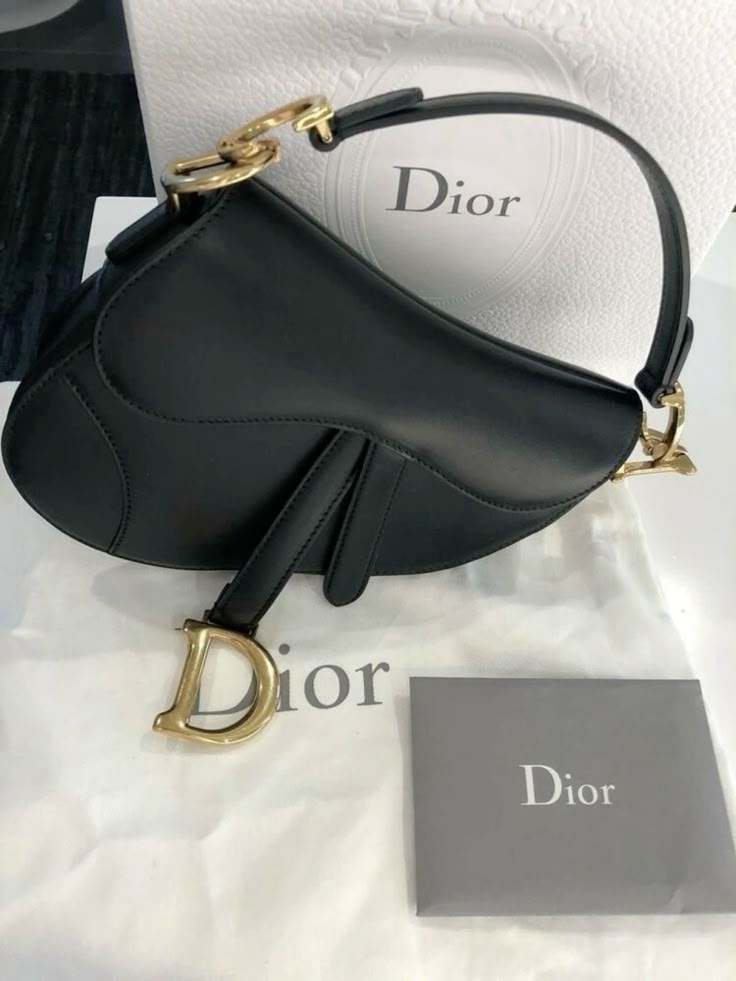 Elegant black Dior handbag with gold accents, displayed on branded packaging.