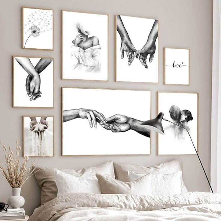 Gallery wall of hand-drawn art featuring hands, a couple, and dandelions above a cozy bed with a modern lamp.