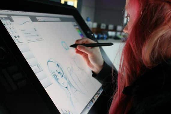 Artist drawing on digital tablet with stylus, creating a character illustration.
