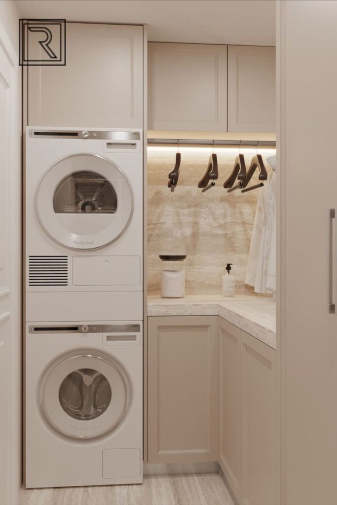 Compact laundry room with stacked washer and dryer, beige cabinets, and hanging space.