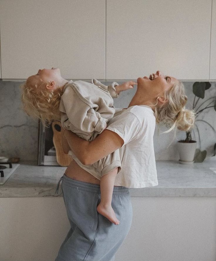 Mother and child laughing together in a kitchen, creating joyful family bonding moments.