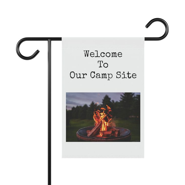 Campground welcome sign with a burning campfire image in a scenic outdoor setting.