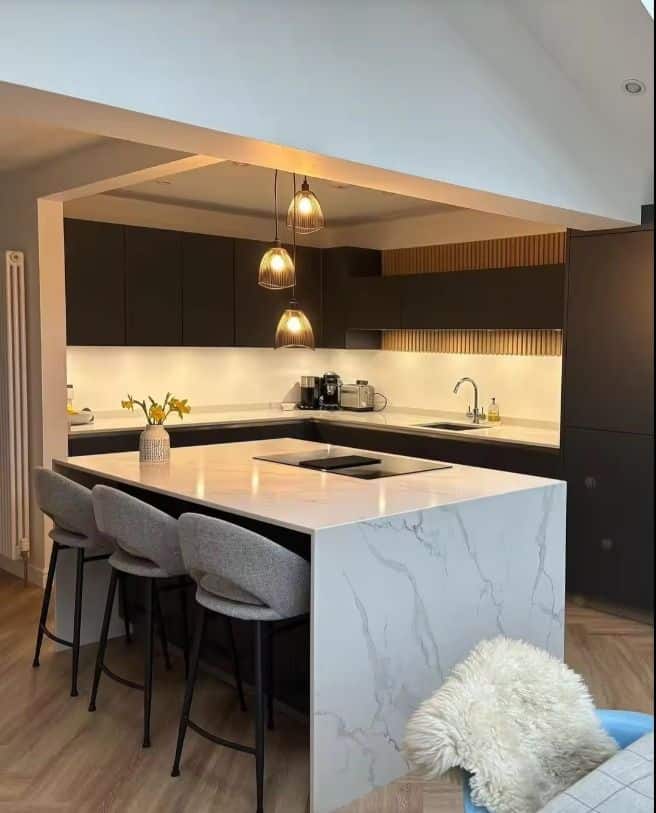 Modern kitchen with marble island, pendant lighting, and sleek black cabinets for a contemporary design look.