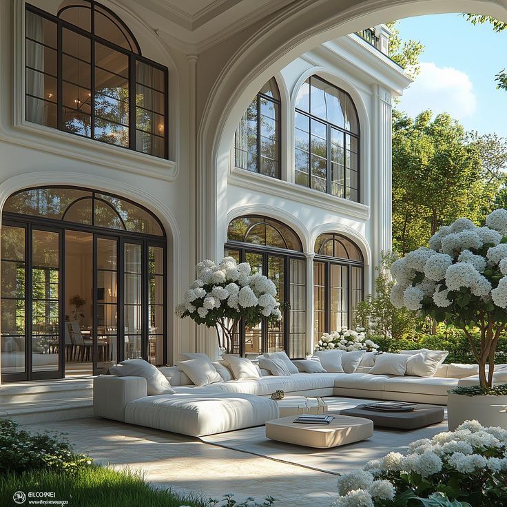 Luxurious modern patio with white sofa, elegant arches, and blooming hydrangeas surrounded by lush greenery.