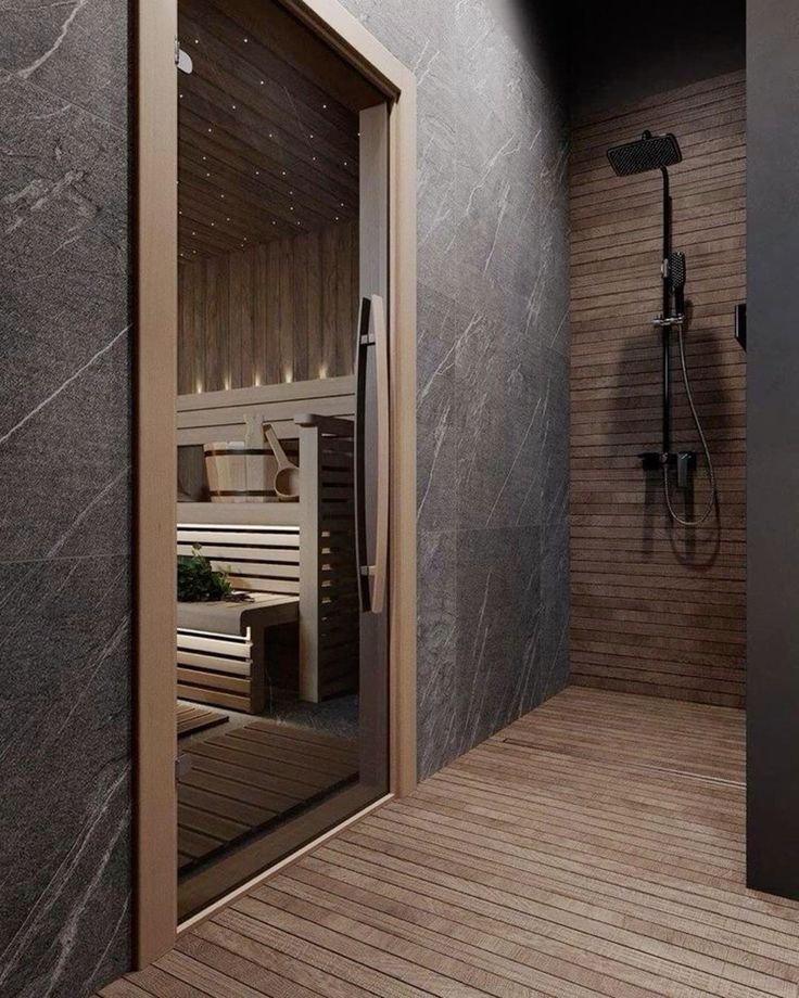 Modern bathroom with wood and stone finishes, featuring a shower and a sauna visible through a glass door.