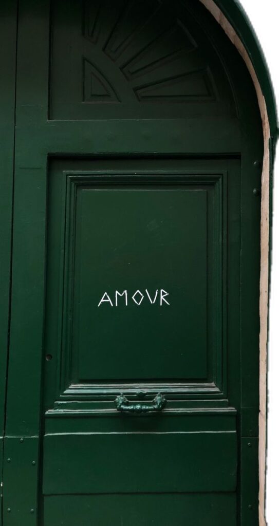 Green door with AMOUR written in white, symbolizing love and mystery. Elegant decor above the door adds charm.