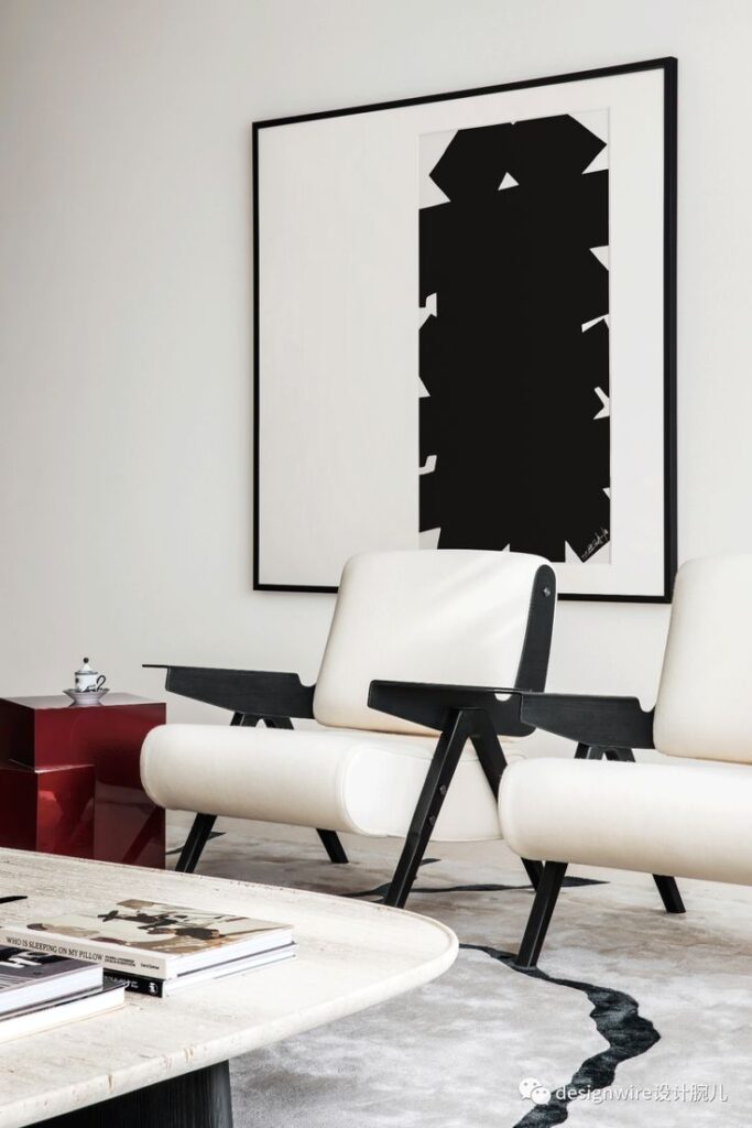 Minimalist living room with abstract black and white art, modern chairs, and coffee table.