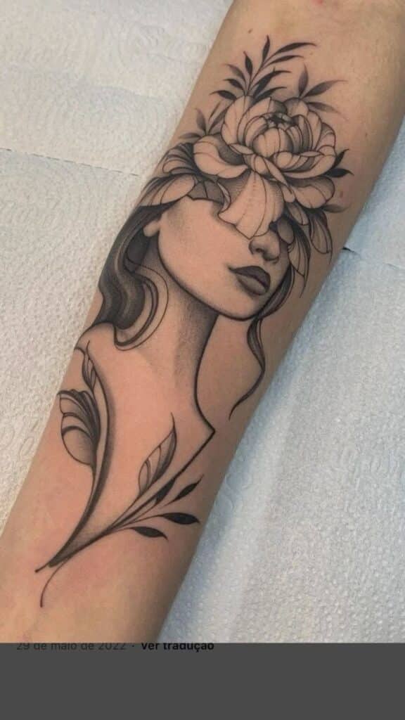 Floral face tattoo with detailed shading on an arm, showcasing artistic design of flowers and leaves.
