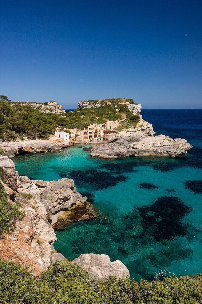 Scenic coastal view of turquoise waters and rocky cliffs in Mallorca, Spain, under a clear blue sky.