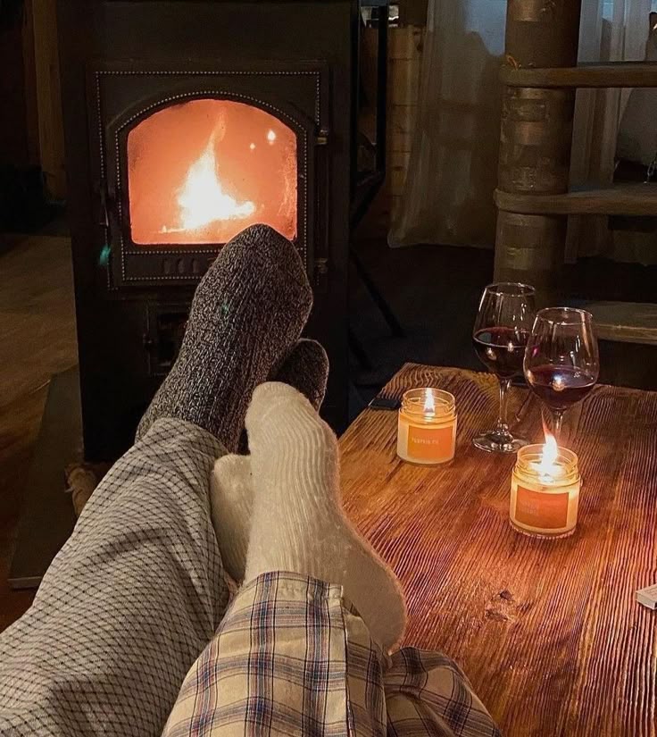 Cozy evening by the fireplace with wine, candles, and feet in warm socks.