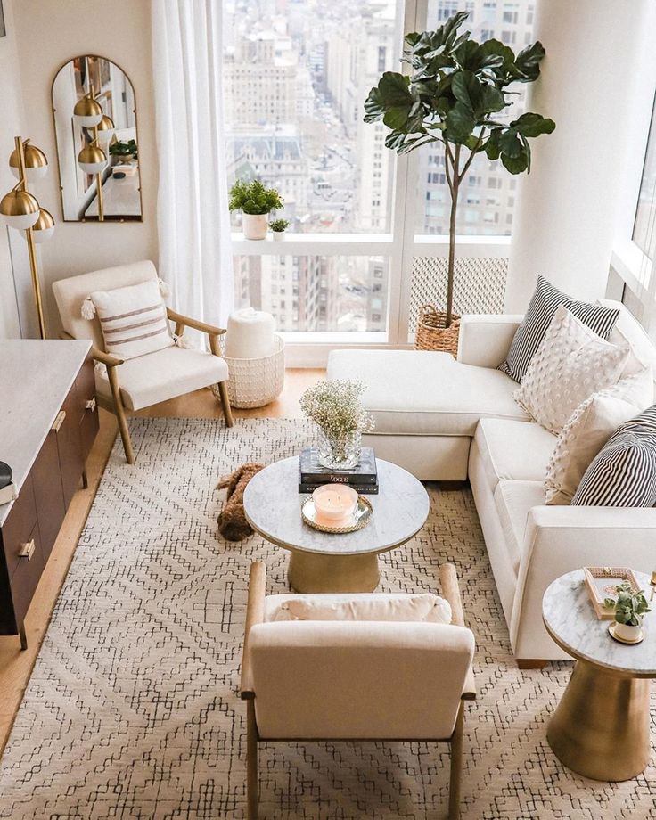 __blush velvet Stylish living room with modern furniture, cozy decor, and large windows overlooking a cityscape. | Sky Rye Design Stylish living room with modern furniture, cozy decor, and large windows overlooking a cityscape.