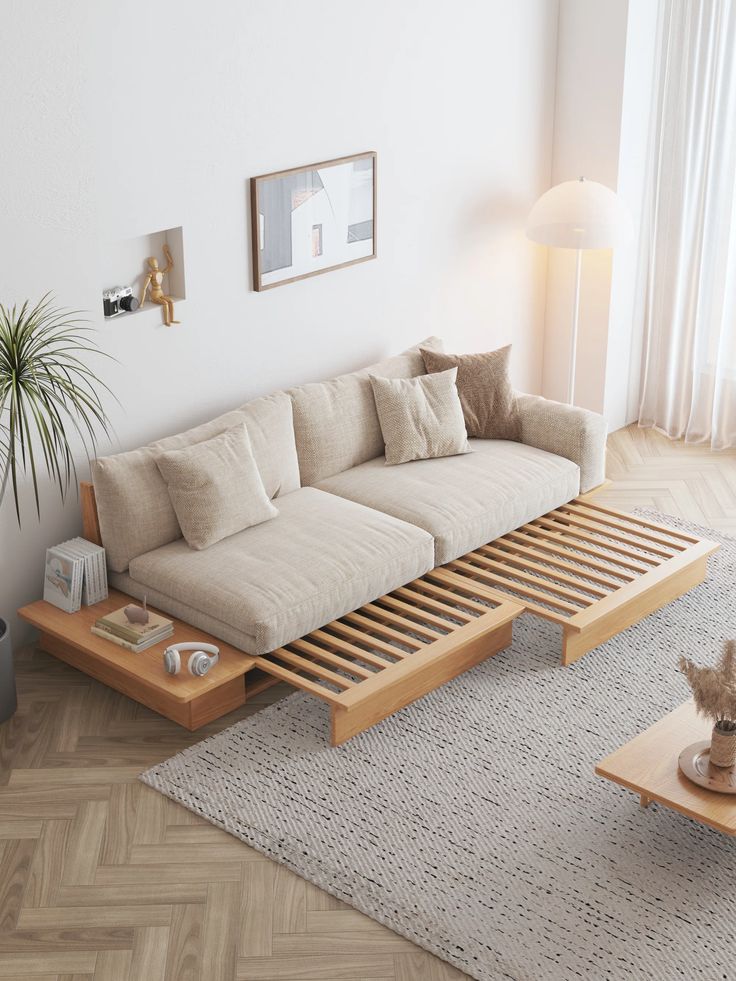 Modern minimalist living room with beige sofa, wooden platform, cozy rug, and tall lamp by large window.