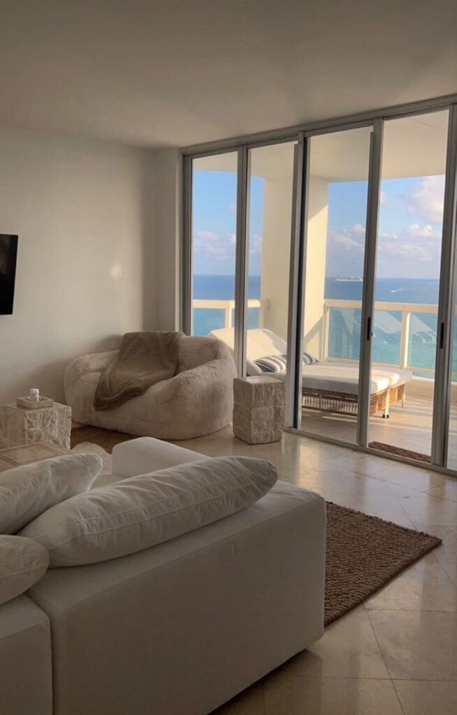 Cozy living room with ocean view balcony, plush furniture, and soft lighting, perfect for relaxation.
