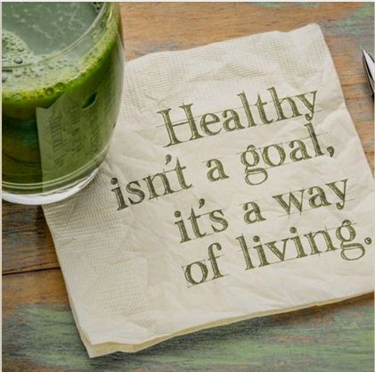 Green juice beside napkin with 'Healthy isn't a goal, it's a way of living' quote, emphasizing lifestyle wellness.
