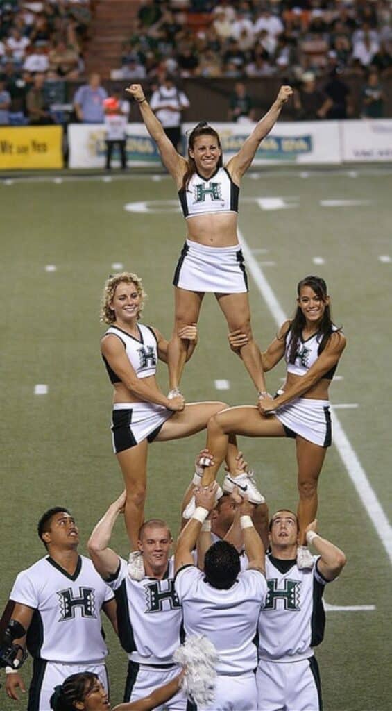 Cheerleaders perform a pyramid stunt at a sports event, showcasing teamwork and athletic skill.